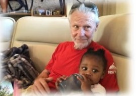 A grandfather in a red shirt holding a baby
