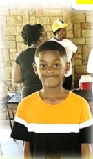 A smiling boy in a yellow shirt