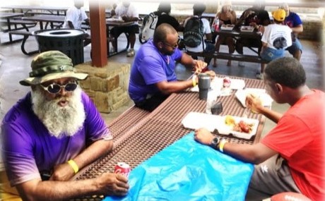 A bearded elder in a purple shirt at the picnic table