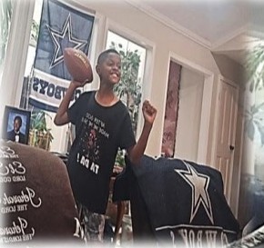 A young fan winding up to throw a football in a room decorated with Cowboys flags