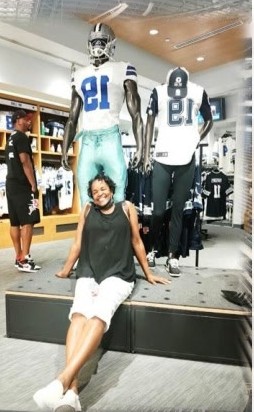 Family member posing in the Cowboys pro shop beside player mannequins