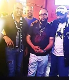 Four men posing together, one in a Cowboys jacket